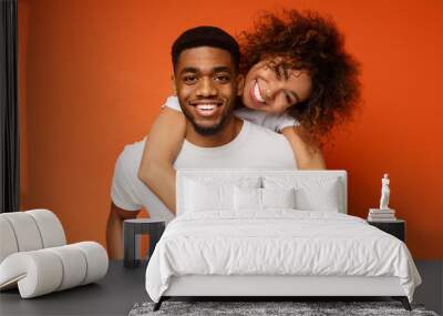 Cute couple in love embracing on orange background Wall mural