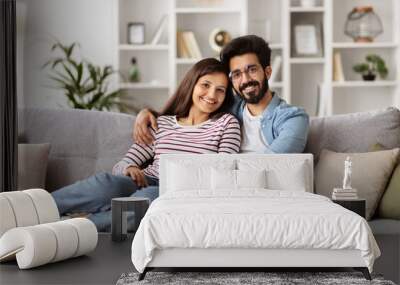 Cute hindu millennial couple sitting on couch at home Wall mural