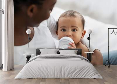 Cute little African American baby drinking from baby bottle Wall mural