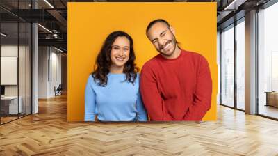 Cute millennial couple posing together on orange background Wall mural