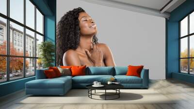 Delighted beautiful afro girl enjoying touching her soft skin Wall mural