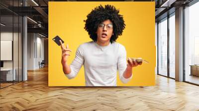 Displeased black guy shrugging with credit card and phone Wall mural