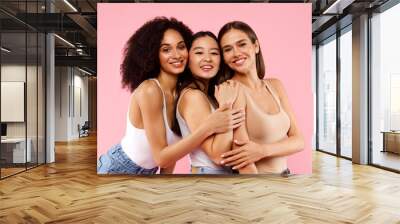 Diverse beauty. Portrait of happy black, asian and caucasian ladies posing and smiling at camera over pink background Wall mural