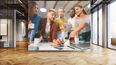 Diverse group of young professionals working together on design ideas, reviewing color options at a table in a bright, contemporary office space. Wall mural