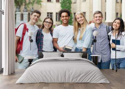 Diverse students in campus, posing in front of university Wall mural