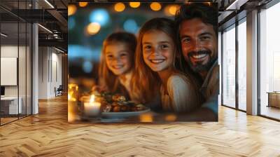 During a warm evening, a father shares laughter and delicious food with his two daughters at a cozy outdoor table adorned with candles, creating a cheerful atmosphere. Wall mural