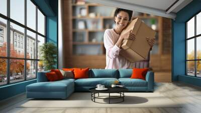 Ecstatic young woman embracing box with something inside Wall mural