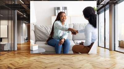 Effective therapy. Cheerful female patient and psychologist shaking hands at office Wall mural