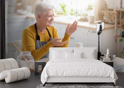 Elderly woman food blogger recording her cooking on smartphone Wall mural