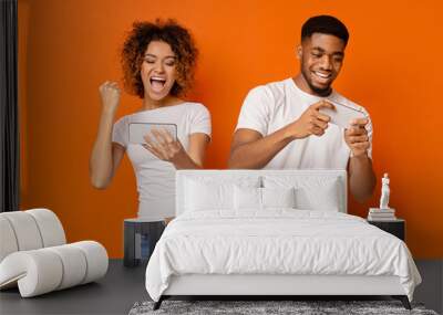 Emotional african american man and woman playing on smartphones Wall mural