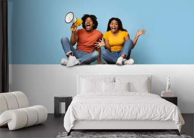 Emotional black couple sitting on empty horizontal board for advertisement Wall mural