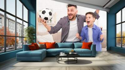 Emotional dad and son with football ball watching sport on tve Wall mural