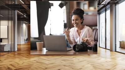 Emotional millennial woman photographer having business call, using laptop Wall mural