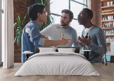 Emotional young guys having quarrel at office Wall mural