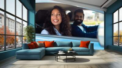 Enjoying travel concept. Smiling arab man driving car, selective focus on happy lady sitting on front passenger seat Wall mural