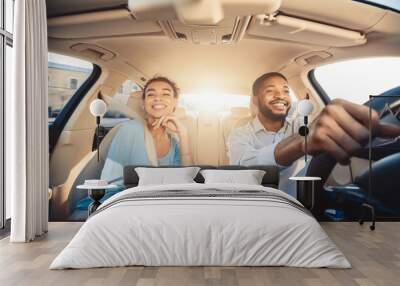 Enjoying travel. Excited african couple driving car Wall mural