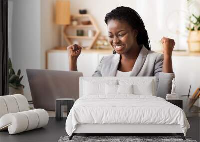 Excited African American Businesswoman Celebrating Success, Looking At Laptop Screen And Shaking Fists At Workplace In Modern Office, Free Space Wall mural