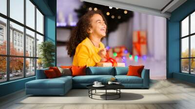 Excited african girl laughing with Christmas gift Wall mural