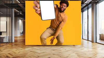 Excited black guy holding smartphone, jumping up Wall mural