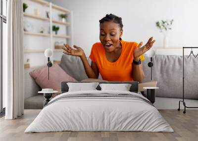 Excited black lady receiving parcel, opening cardboard box at home, satisfied with cool purchase Wall mural