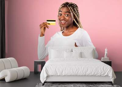 Excited black woman holding credit card showing thumbs up Wall mural