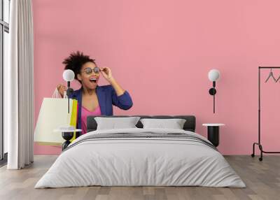 Excited black woman holding shopping bags at studio Wall mural