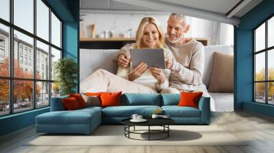 Excited smiling senior spouses using digital tablet computer at home Wall mural