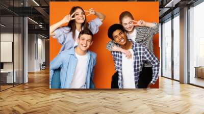 Excited teen guys giving piggyback ride to girls Wall mural