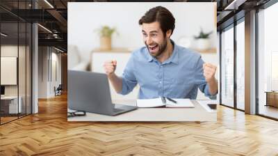 Excited Young Businessman At Laptop Computer Shaking Fists In Office Wall mural