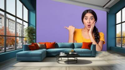 Excited young indian woman pointing aside at copy space Wall mural