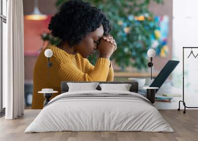 Exhausted african girl sitting in cafe, looking for job online Wall mural