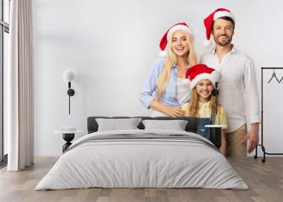 Family Of Three In Christmas Santa Hats Standing In Studio Wall mural