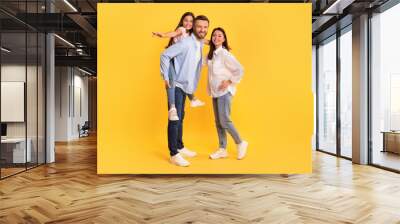 family posing together kid daughter piggybacking and spreading arms, studio Wall mural