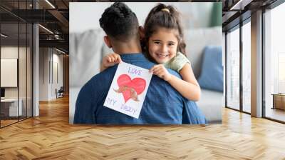 Father's Day Concept. Smiling little girl embracing dad and holding greeting card Wall mural