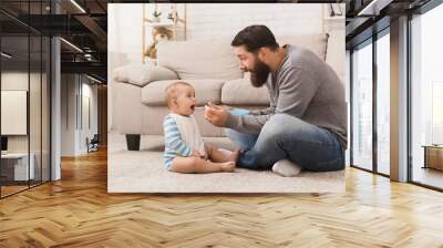 Father feeding his cute baby son at home Wall mural