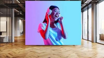 Favorite music online. Girl in modern headphones sings with eyes closed Wall mural