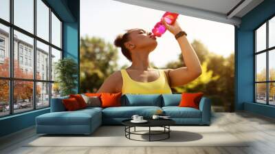 Fit black woman in yellow sportswear drinking water Wall mural