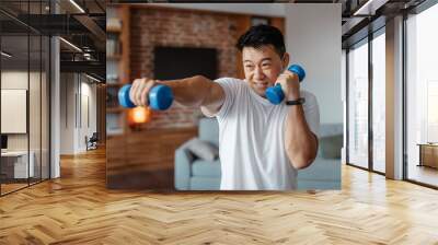 Fitness and sport concept. Active mature man exercising with two dumbbells and boxing, enjoying domestic workout Wall mural