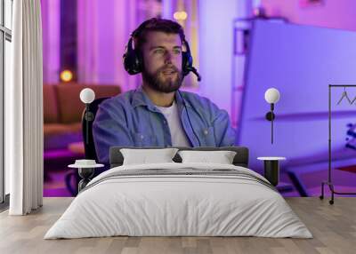 Focused gamer using PC in neon-lit room Wall mural