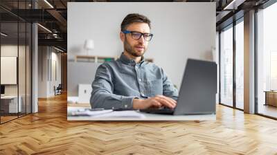 Focused mature businessman working with laptop computer at his desk in office, typing on pc keyboard, checking email Wall mural