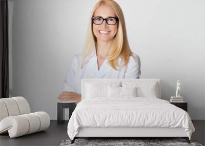 Friendly woman doctor in white uniform, smiling to camera Wall mural