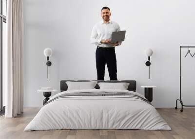 Full length portrait of middle aged businessman using laptop computer for online work, grey studio background Wall mural