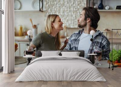 Glad happy handsome caucasian millennial couple eat pasta together, have fun in light kitchen interior, profile Wall mural