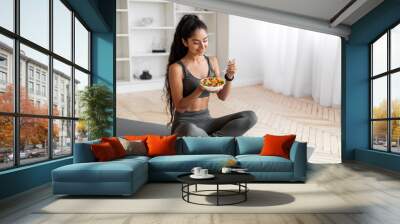 Good-looking athletic millennial woman have lunch after exercising at home Wall mural