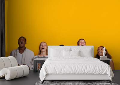 Group of surprised students with smartphones over yellow background Wall mural