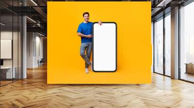 Guy pointing and leaning on big white empty smartphone screen Wall mural