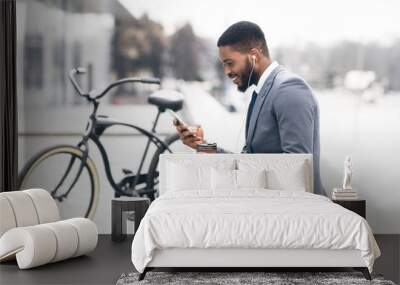 Handsome afro businessman texting on phone during coffee break Wall mural