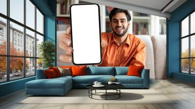 Handsome arab guy showing phone with empty screen, mockup Wall mural