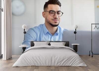 Handsome Arab man using laptop pc, searching info on web at modern office Wall mural