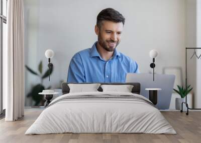 Handsome male entrepreneur working on laptop at desk in modern office Wall mural